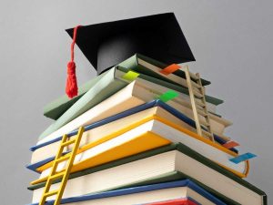 Pila de libros con un birrete de graduación en la parte superior