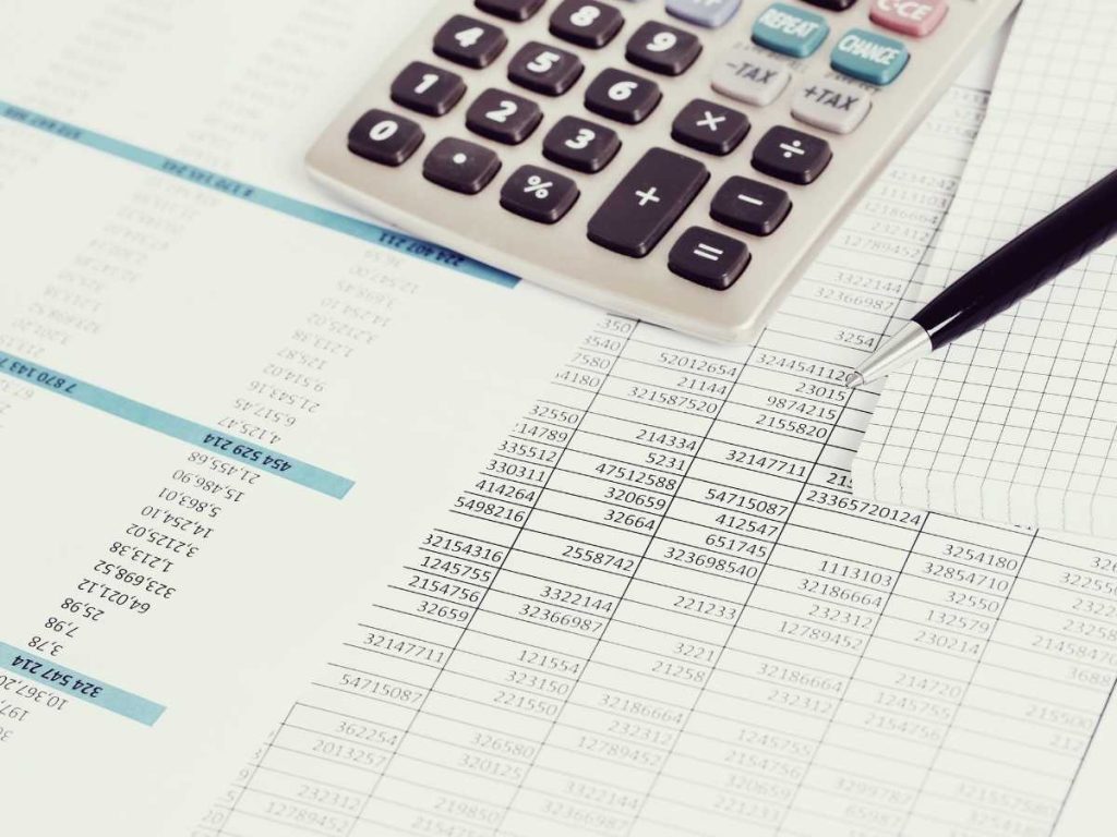 Análisis del precio para realizar un trabajo fin de grado con una calculadora y documentos financieros.