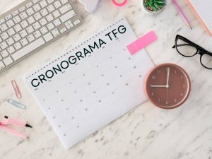 Vista desde arriba de un escritorio con un calendario y herramientas de planificación, ideal para crear un cronograma TFG efectivo.