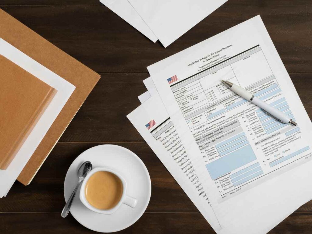 Papel, bolígrafo y café en un escritorio con documentos de TFG