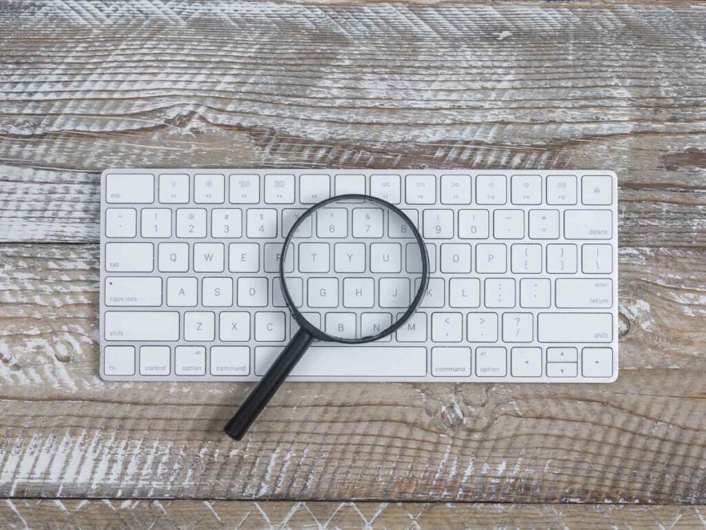 Lupa encima de un teclado de ordenador en busca de plagio.