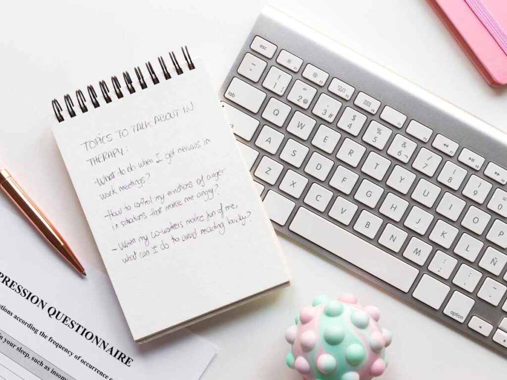 Teclado de ordenador y una libreta con palabras clave del TFG.