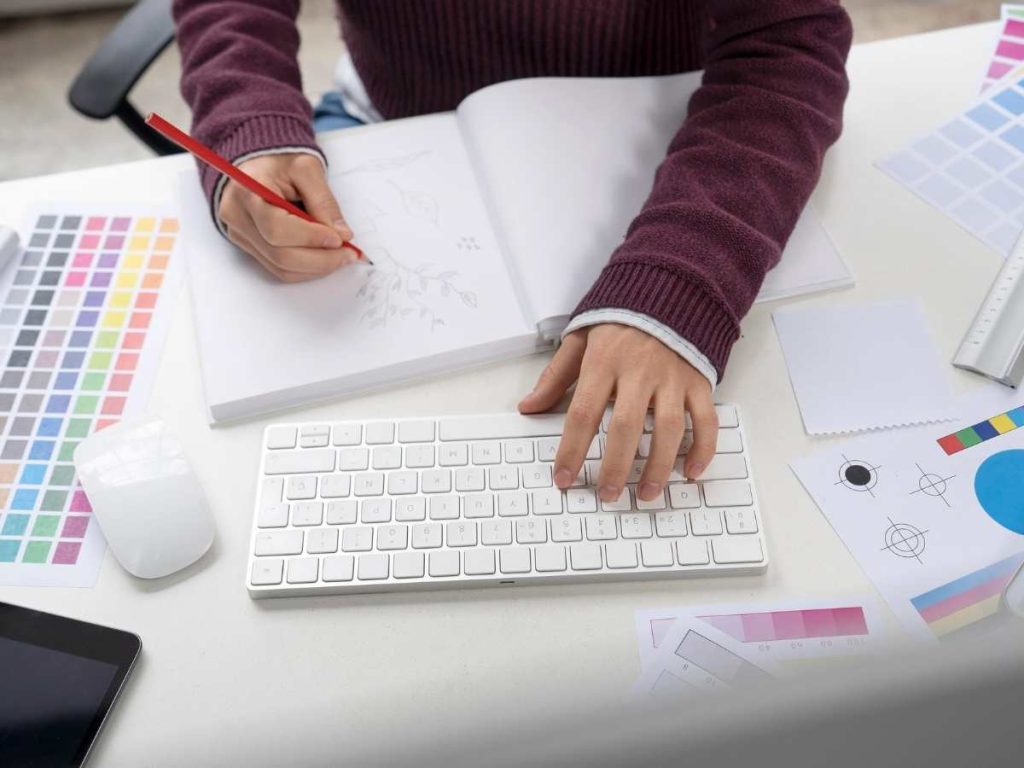 Trabajo de diseño gráfico, mesa de trabajo con herramientas de diseño y colores.